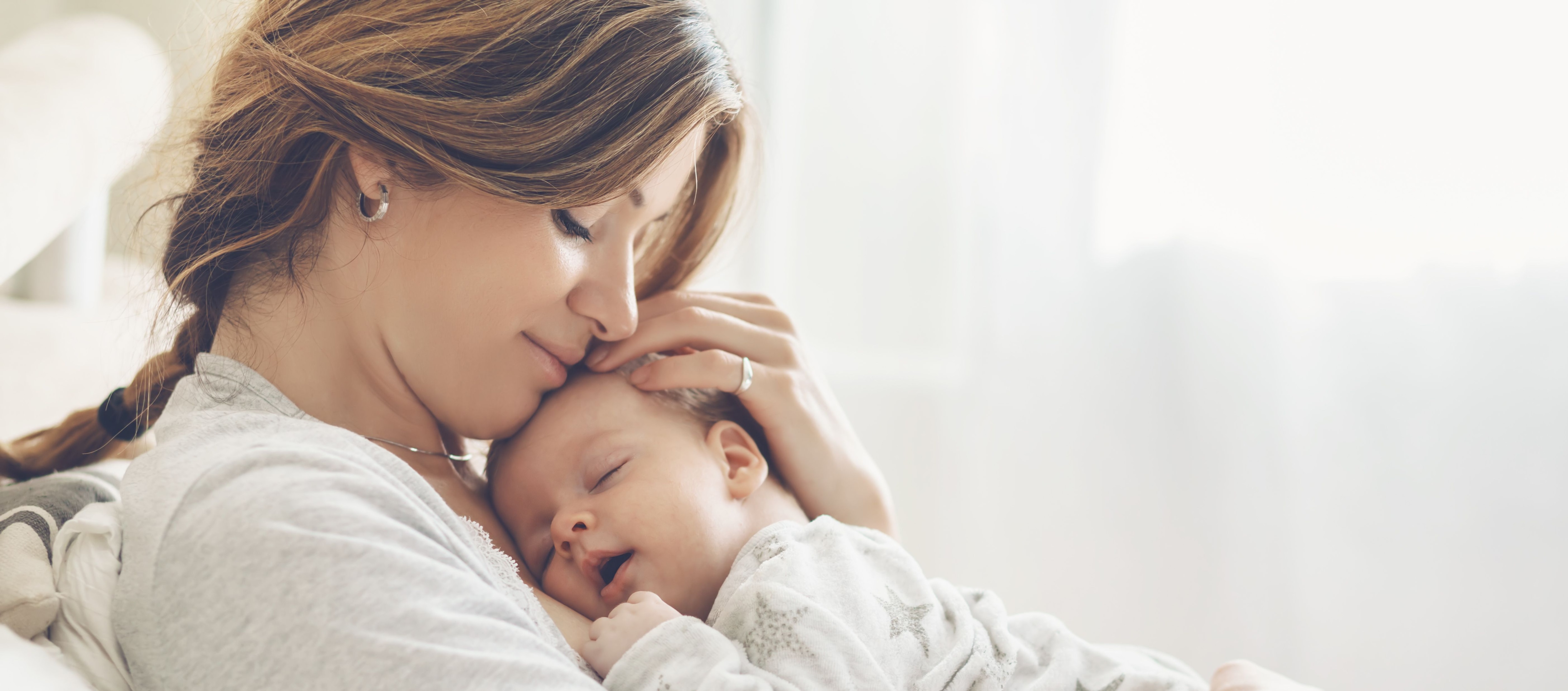 Mother holding and kissing her baby boy on the cheek