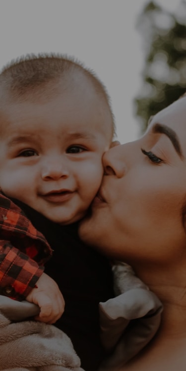 Mother holding and kissing her baby boy on the cheek